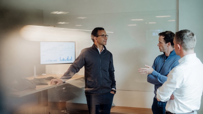 Photo of three people standing by a desk